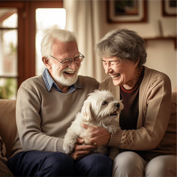 couple de personnes âgées souriant et jouant avec leur chiot